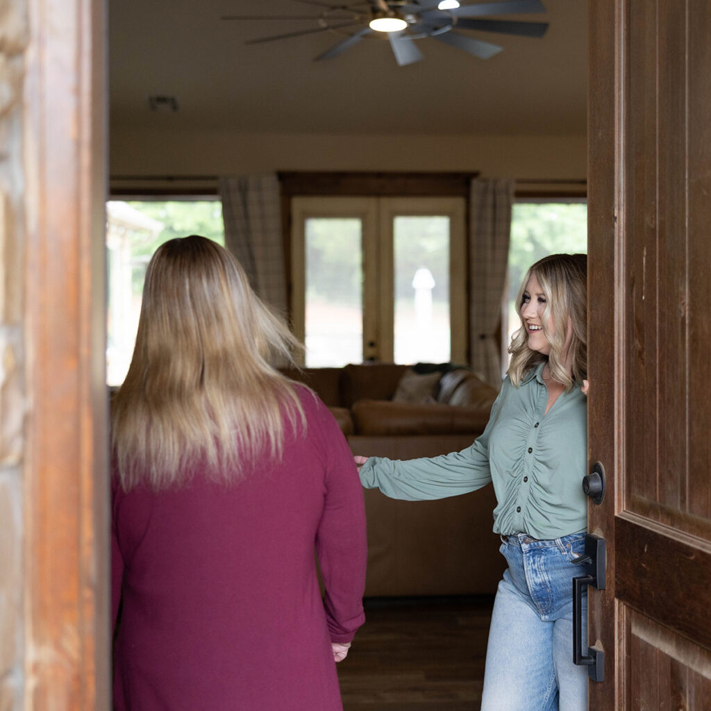 Real estate agent welcoming a potential buyer into a home to help you sell your home.